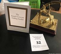 Sundial on base with booklet and lot card visible