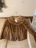 Front view of brown fur jacket on hanger