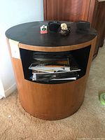 Front view of cylindrical teak end table showing open cubby and teak veneer