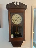 Full view of oak cased wall clock hanging on wall
