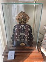 Front view of skeleton wagon spring clock inside glass case