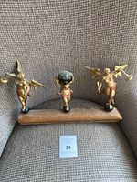 Three gilt statues on wooden bar displayed on chair