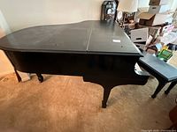 Full side view of ebony grand piano on carpeted floor