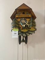 Front view of cuckoo clock showing chalet case, dial, trees, weights