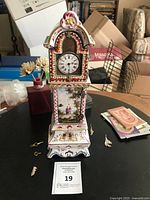 Front view of faience clock showing dial, painted scenes, two winding keys