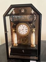 Front view showing clock face, columns, painted frieze and display case