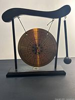 Front view of brass zodiac gong on wood stand with mallet