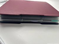 Closed maroon binder, spine view showing thickness of filled pages