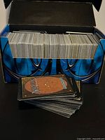 Open cardboard Magic: The Gathering storage box filled with upright cards, loose stack in foreground