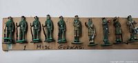 Full view of eleven Gurkha figurines on cardboard strip