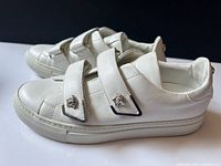 Left side view of both sneakers showing Velcro straps and Medusa hardware