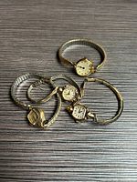 All four wristwatches laid flat showing cases and bands