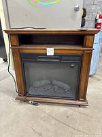 Front view of electric fireplace heater showing cabinet, glass panel, controls, and cord