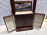 Full view of jewelry box open with drawers, side doors and mirror visible