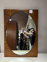 Full view of rectangular wood frame with oval mirror