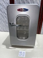 Front view of silver StorZcool mini fridge with glass door and chrome handle