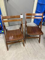 Full view of both wooden folding chairs standing upright