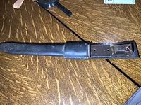 Bayonet sheathed in leather scabbard on wood surface