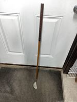 Full view of the antique wood-shaft putter leaning upright