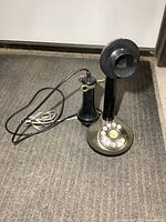 Full view of black and brass-tone candlestick telephone with cords