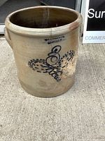 Front of crock showing Skinner & Co. stamp, cobalt decoration, chipped area