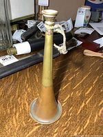 Full view of copper and brass bugle standing upright on table
