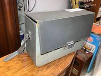 Closed grey hard carry case with shoulder strap