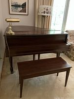 Front view of baby grand piano with bench