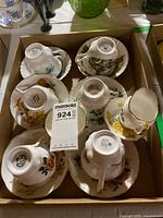 Box containing seven inverted teacups on their saucers