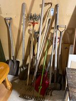 Full group of long-handled tools leaning against wall