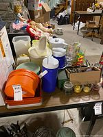Overview of table with plastic containers, Thermos jugs, glasses, votives