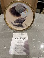 Front of Bald Eagle collector plate on stand with certificate showing artwork and gold rim