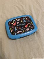 Closed Bentgo Kids lunch box showing blue border and dinosaur print lid