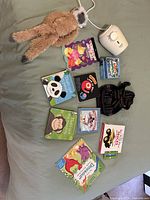 All items laid out on bed: bottle warmer, plush sloth, knit pouch, multiple board books visible