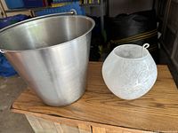 Metal bucket and IKEA frosted glass light shade displayed on wood surface