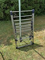Full view of collapsible stainless-steel tone drying rack standing upright on lawn