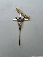 Front view of gold-tone crucifix stake and raffia tie