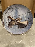 Front view of plate on stand showing artwork and gold rim