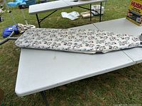 Ironing board folded on table showing floral cover and metal frame