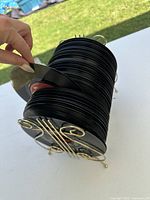 Side angle of cylindrical stack of 7-inch records on gold-tone stand outdoors