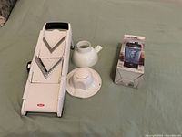 Mandoline slicer, food holder, pitcher-shaped tornado cup component and boxed cup displayed on surface