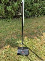 Full view of Bissell manual carpet sweeper standing upright on lawn