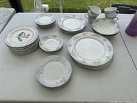 Assortment of plates, saucers, and teacups with various floral and botanical patterns displayed on table