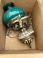 Lamp in box showing turquoise glass shade, metal frame, ceramic lower detail and wiring