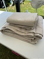 Stack of three folded beige linens on a table outdoors