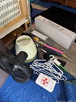 Lot overview showing hair dryer, storage bin, folding table case, umbrellas, hangers, first aid kit and tools