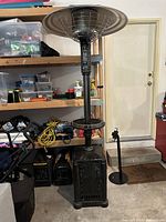 Full view of patio heater showing base, pole, shelf and burner head