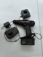 Top view of cordless drill, battery, charger base, and adapter