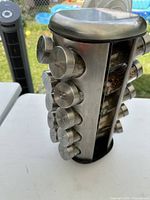 Full view of rotating stainless steel spice rack showing multiple labeled spice jars, one slot empty