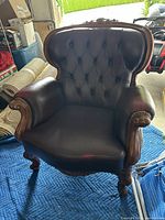 Front view of leather armchair with carved wood frame